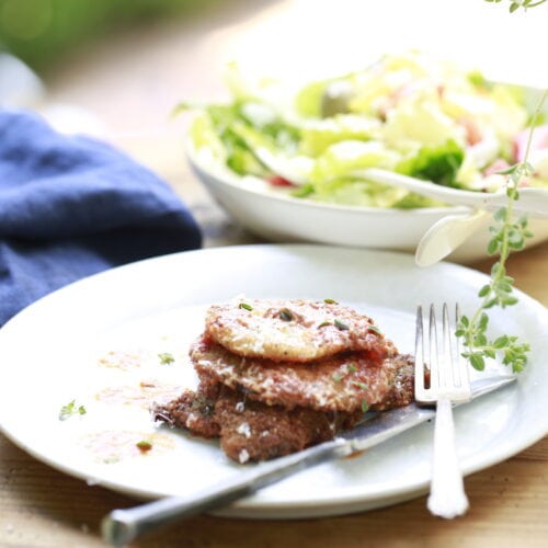 plated venison parmesan on white plate with blue napkin