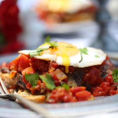open faced fried egg sandwich with venison and tomatoes