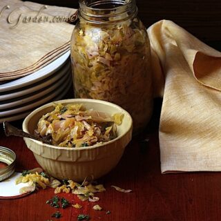 Sauerkraut in a bowl near a glass jar of the same.