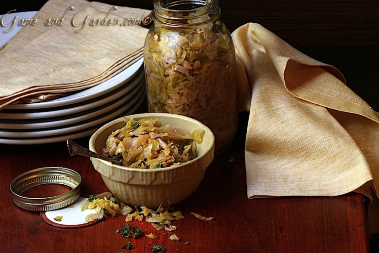 Sauerkraut in a bowl near a glass jar of the same.