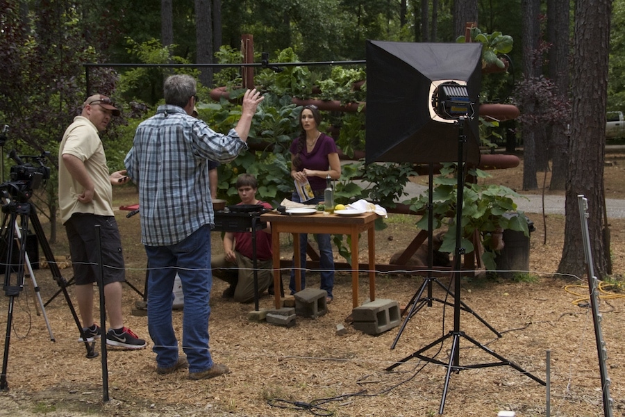 Stacy Lyn Harris filming in front of hydroponics gardening system.