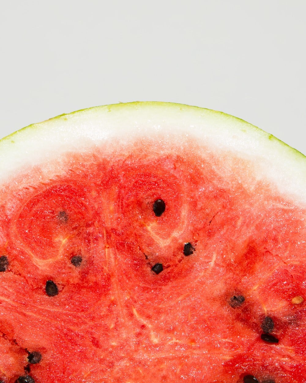 closeup of slice of ripe red watermelon with green and white rind
