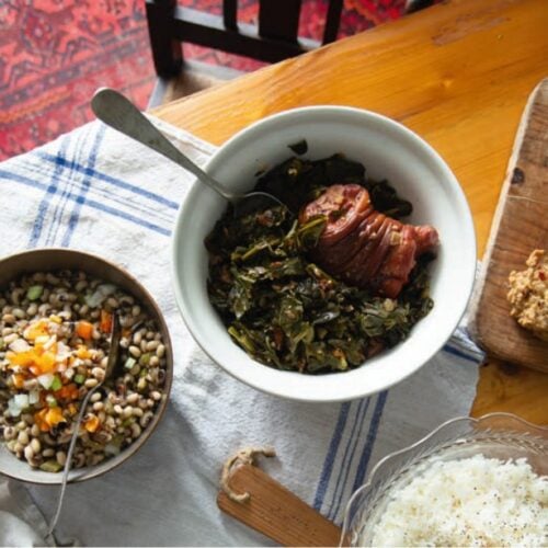 Southern spread featuring collard greens with ham in white bowl