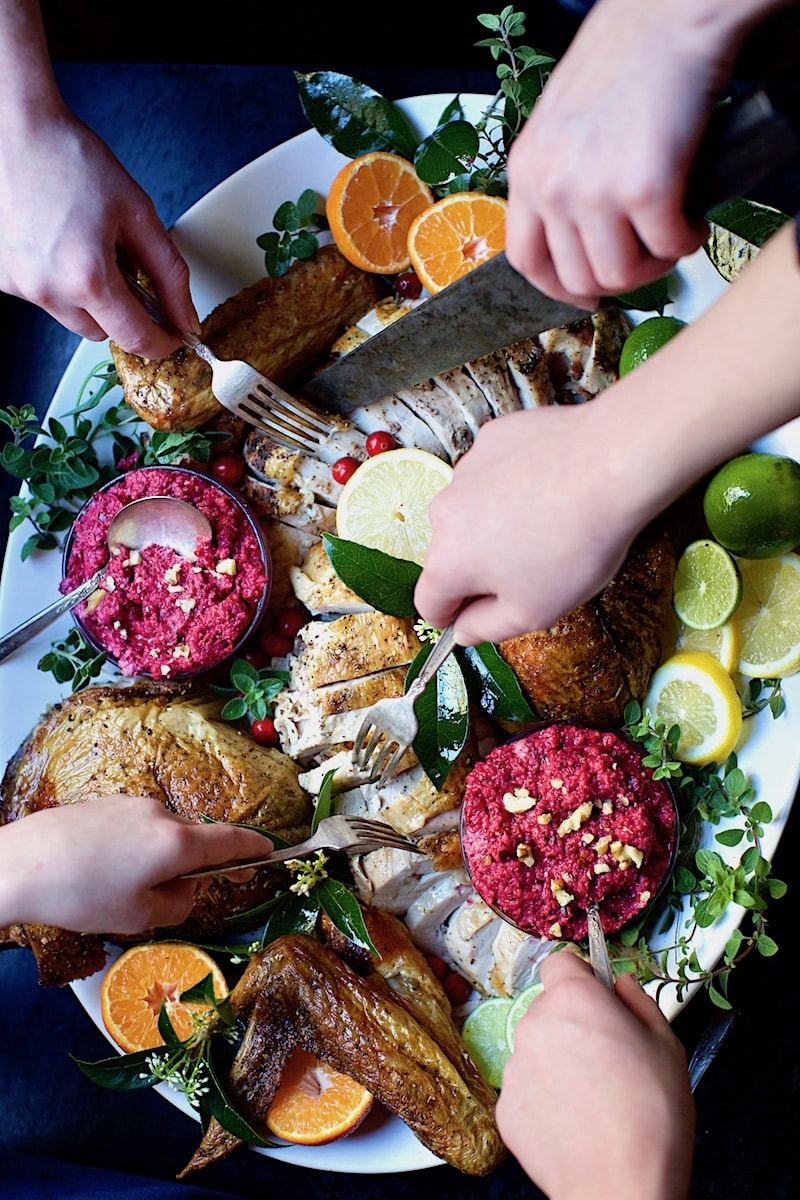 Plate of holiday turkey meat cut with limes and cranberry orange chutney with hands helping themselves