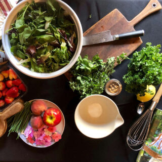 Table setting for herb salad with edible flowers fruits nuts and simple vinaigrette
