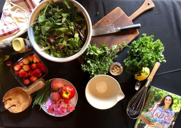Table setting for herb salad with edible flowers fruits nuts and simple vinaigrette