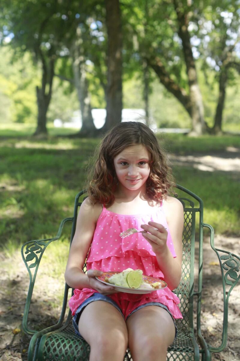 Milly eating key lime cake in a chair under the trees