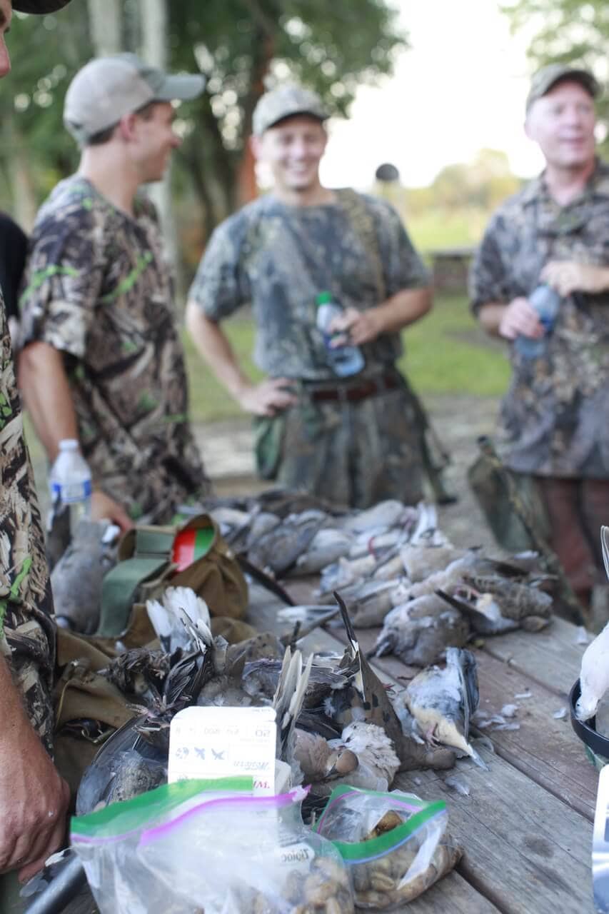 All the participants of the dove hunt gathered around the table covered in mourning doves