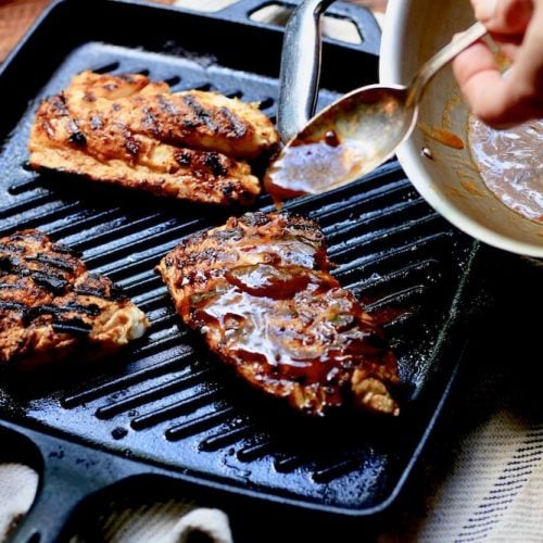 A picture of a spoon drizzling comeback sauce on Stacy Lyn Harris's seasoned Blackened Redfish dish