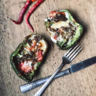 An image of Stacy Lyn Harris's Roasted Bell Peppers Stuffed with Sausage and Cheddar recipe, showing the bell peppers being stuffed with sausage and cheese