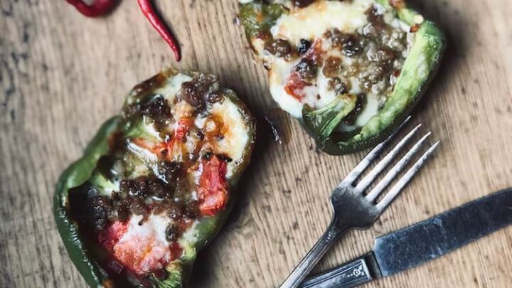 An image of Stacy Lyn Harris's Roasted Bell Peppers Stuffed with Sausage and Cheddar recipe, showing the bell peppers being stuffed with sausage and cheese