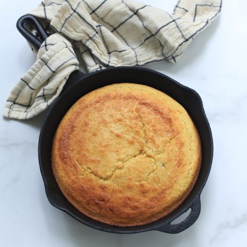 Iron skillet with corn made bread pretty towel.