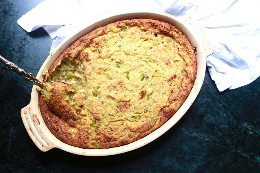 Southern Cornbread Dressing Casserole Recipe in an oval white deep dish with a spoon.