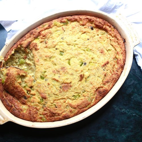 Southern Cornbread Dressing Casserole Recipe in an oval white deep dish with a spoon.