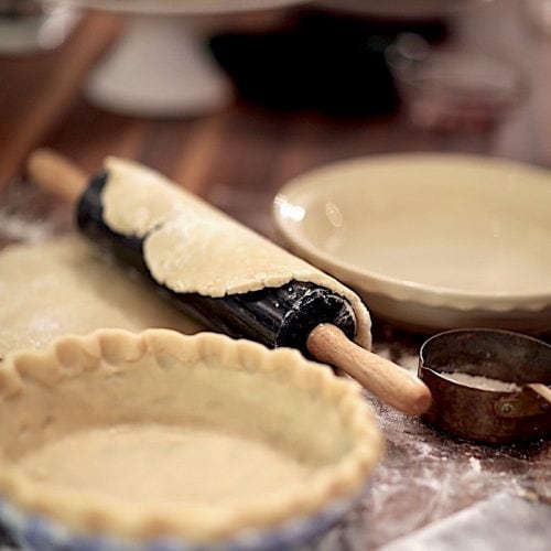 Homemade pie dough in pie shell and rolling pin with pie crust ready to go into pie shell