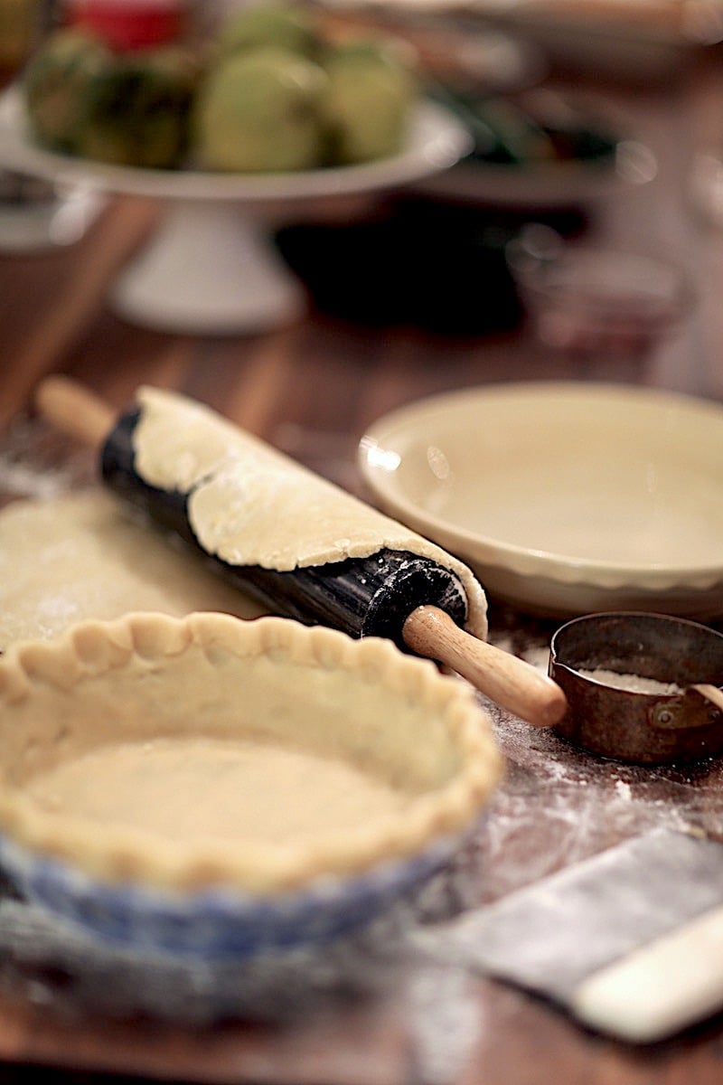 Homemade pie dough in pie shell and rolling pin with pie crust ready to go into pie shell