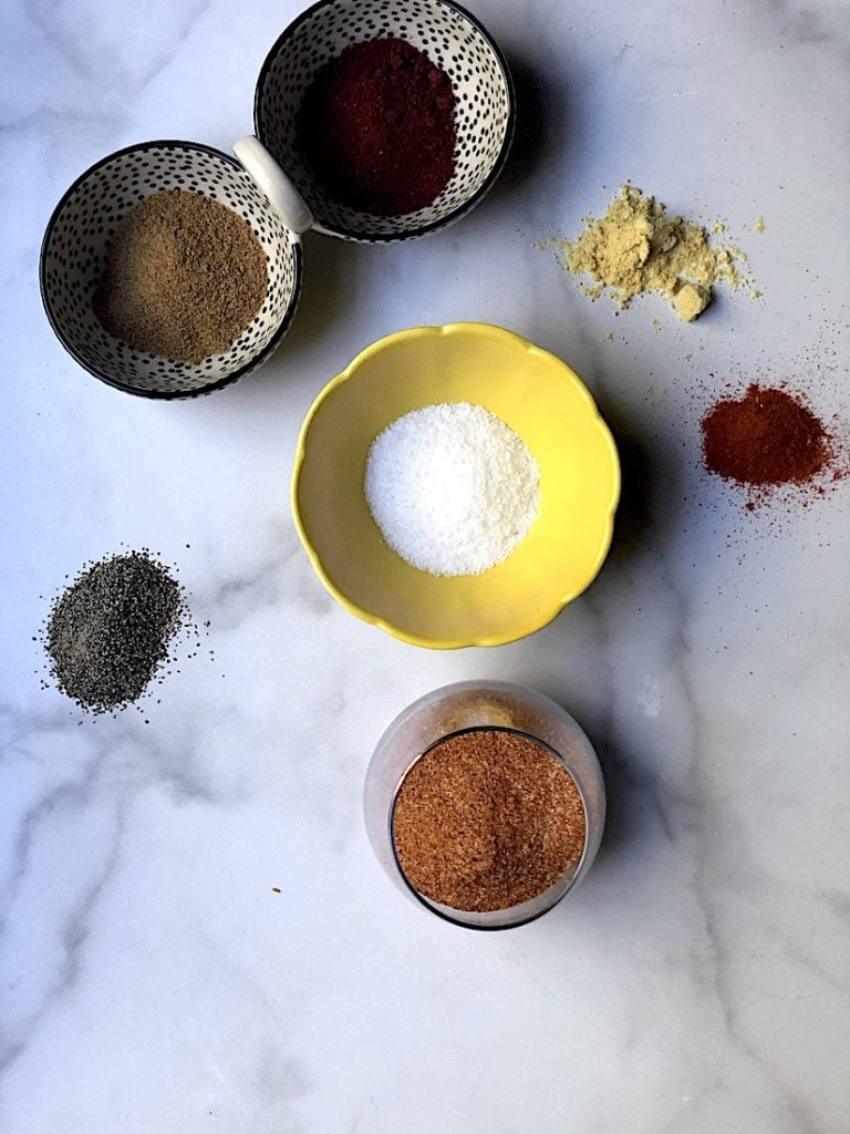 Spices in various dishes to create an all-purpose dry rub on white marble
