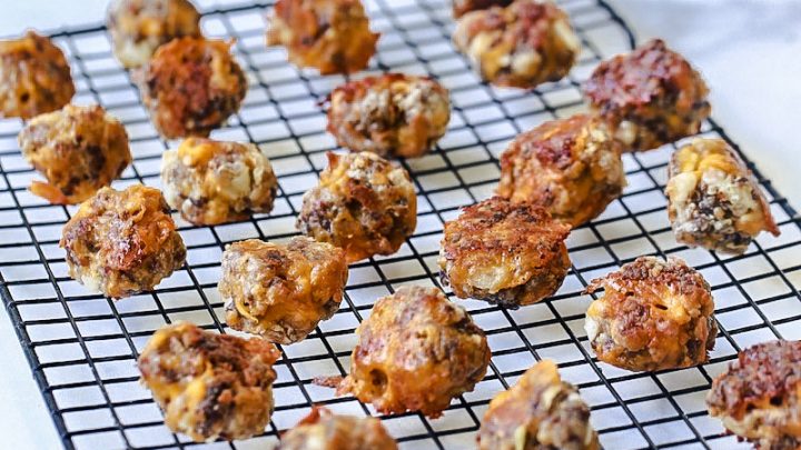 Sausage Balls on a cooling rack on white marble with a plate of sausage balls behind it.