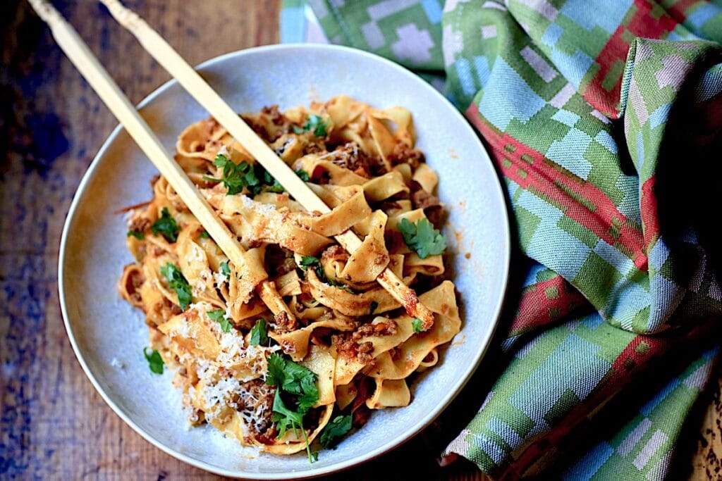 Bolognese in White bowl with Chopsticks on wooden surface with Italian napkin