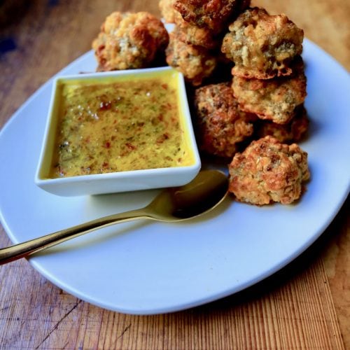 Sausage balls served with mustard red pepper jelly sauce on white plate