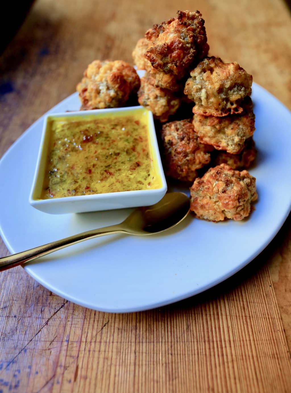 Sausage balls served with mustard red pepper jelly sauce on white plate