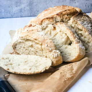 Homemade Crusty Brad on piece of tan parchment paper on white marble with gray background