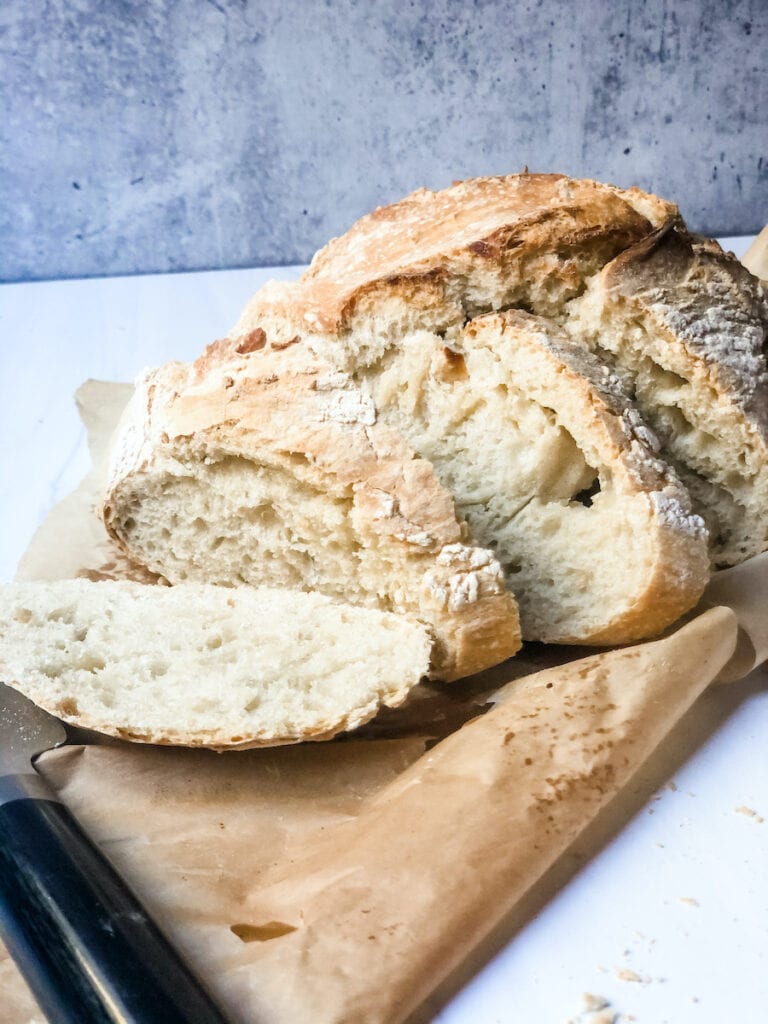 Homemade Crusty Brad on piece of tan parchment paper on white marble with gray background