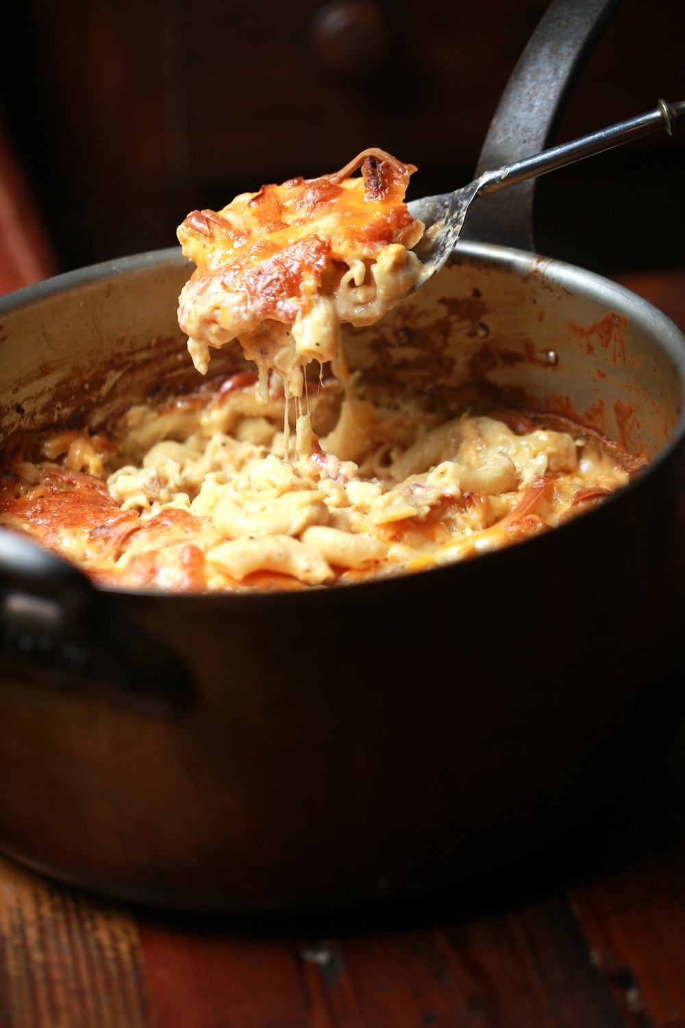 Spoonfull of Mac and cheese held over a copper pot full of crawfish mac and cheese