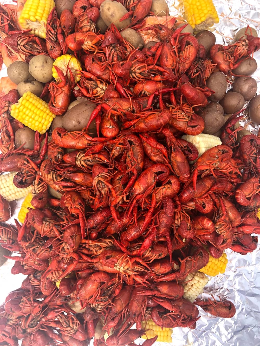 Overhead shot of crawfish, corn, potatoes, and shrimp on foil from crawfish boil recipe