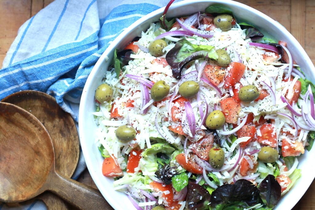 closeup of tossed Italian salad recipe with wooden utensils