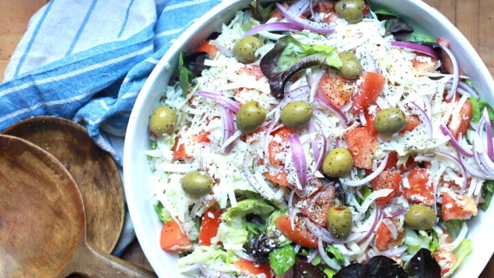 closeup of tossed Italian salad recipe with wooden utensils