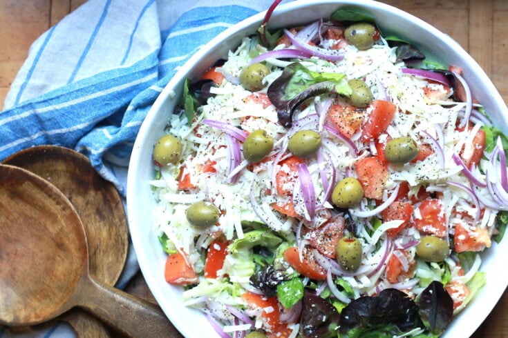 closeup of tossed Italian salad recipe with wooden utensils