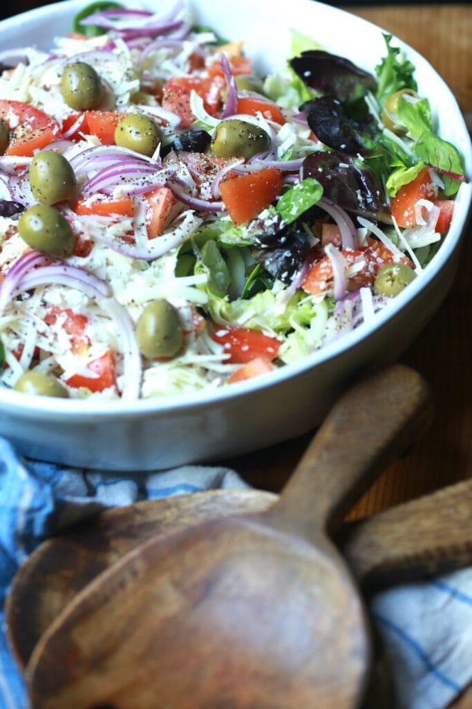 Up close view of fresh Italian salad tossed in white bowl.