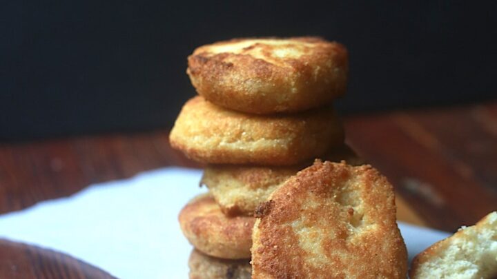 Fried Cornbread aka Hot Water Cornbread or Hoe Cake in parchment paper on wood surface with Black background