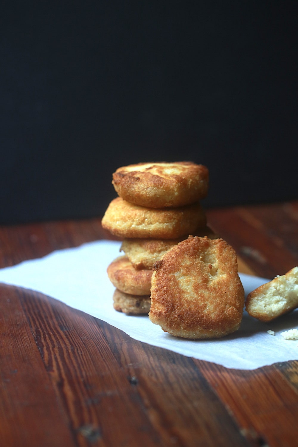 Fried Cornbread aka Hot Water Cornbread or Hoe Cake in parchment paper on wood surface with Black background