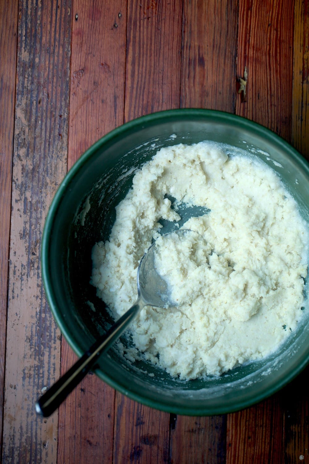 Green bowl of cornmeal batter with spoon