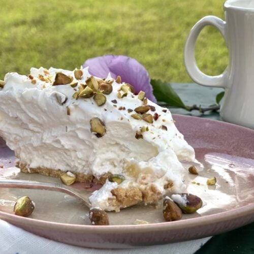 Fork with Bit of Pineapple Pie on a Pink Plate with pie in background with pistachio nuts on top