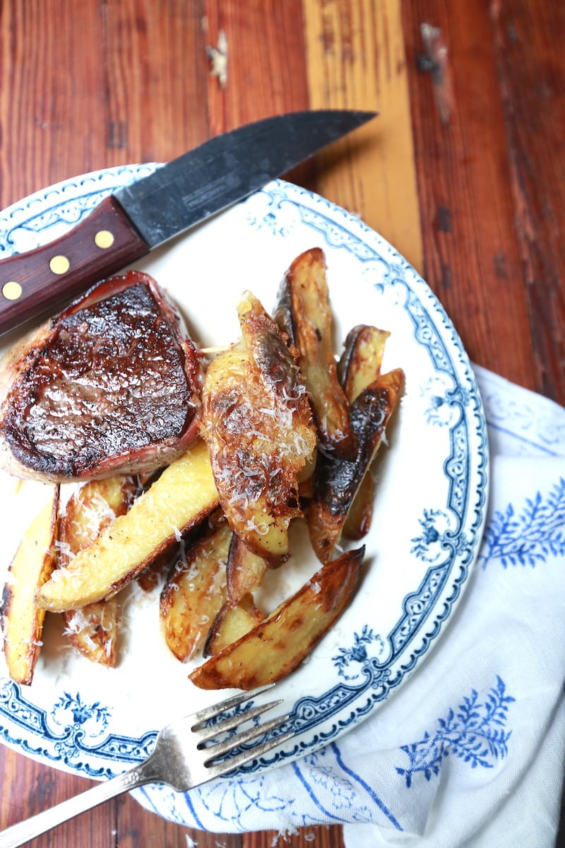 closeup of potato wedge fries on decorative plate with steak