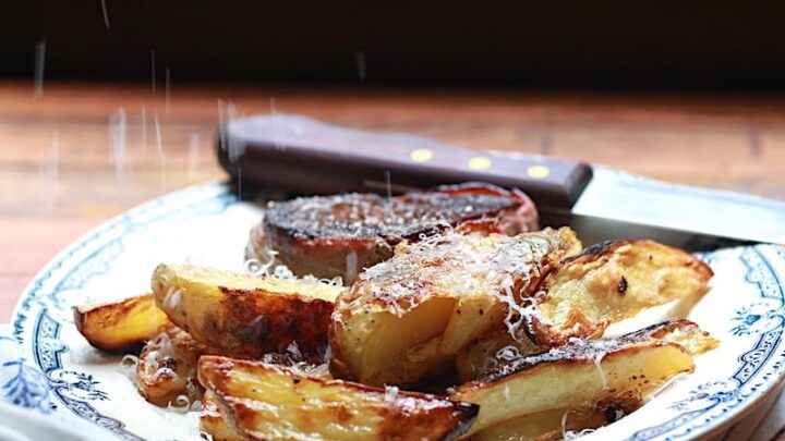 Plate with oven baked wedge fries alongside steak with parmesan