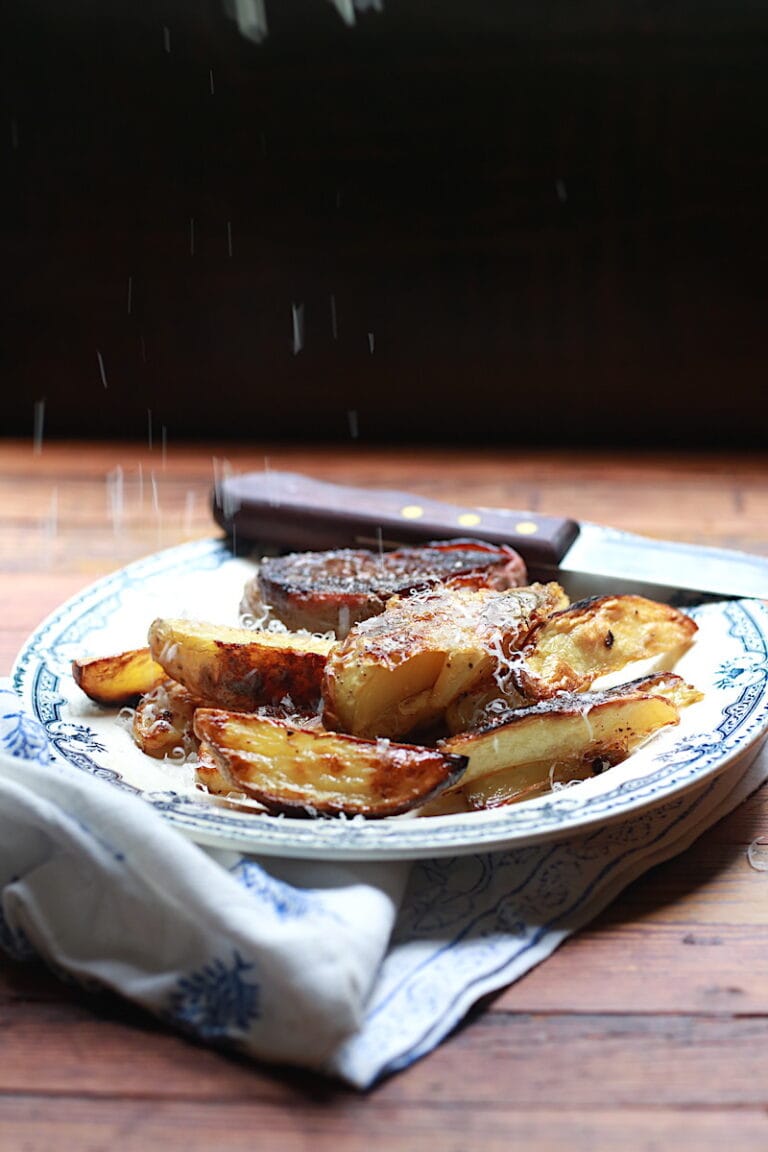 Plate with oven baked wedge fries alongside steak with parmesan