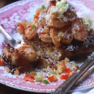 Close up of the pink toile plate with grit cake and shrimp with tons of parmesan cheese piled on top of the shrimp.