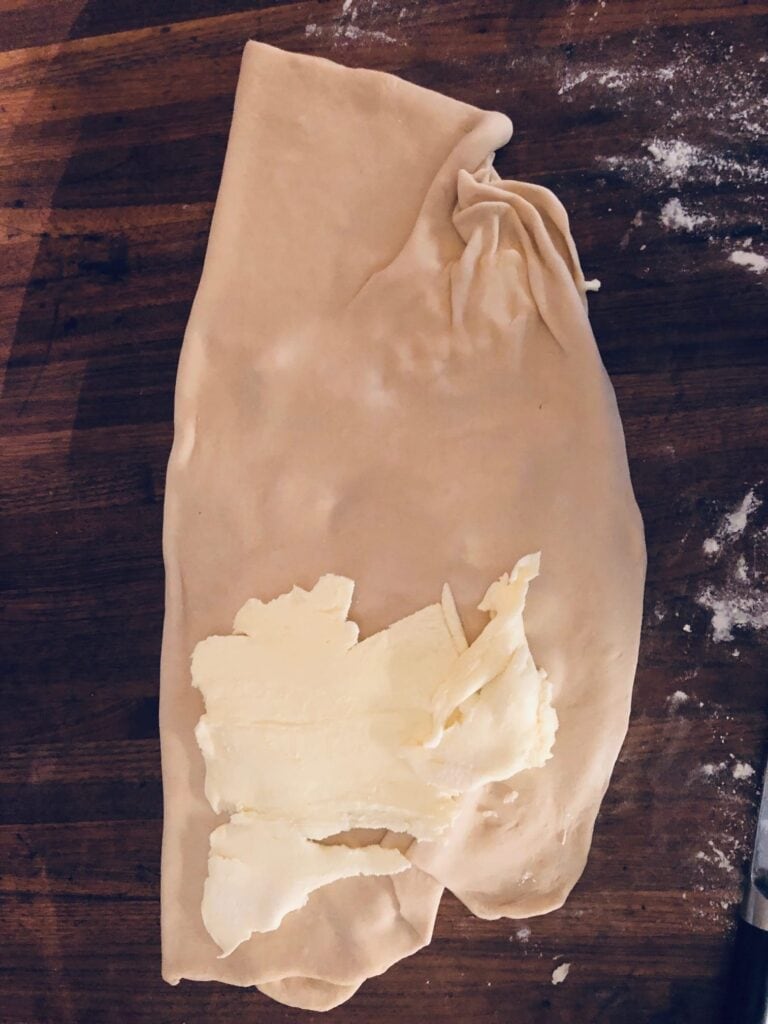 Fold the left side of the dough over the butter. Add the rest of the butter to the lower half of the dough and fold upper half of the dough over the butter.