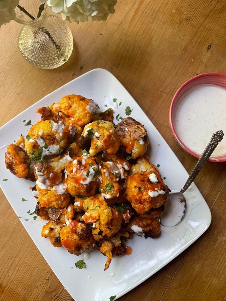 the finished dish - golden cauliflower on white platter with dipping sauce