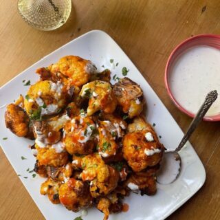 the finished dish - golden cauliflower on white platter with dipping sauce