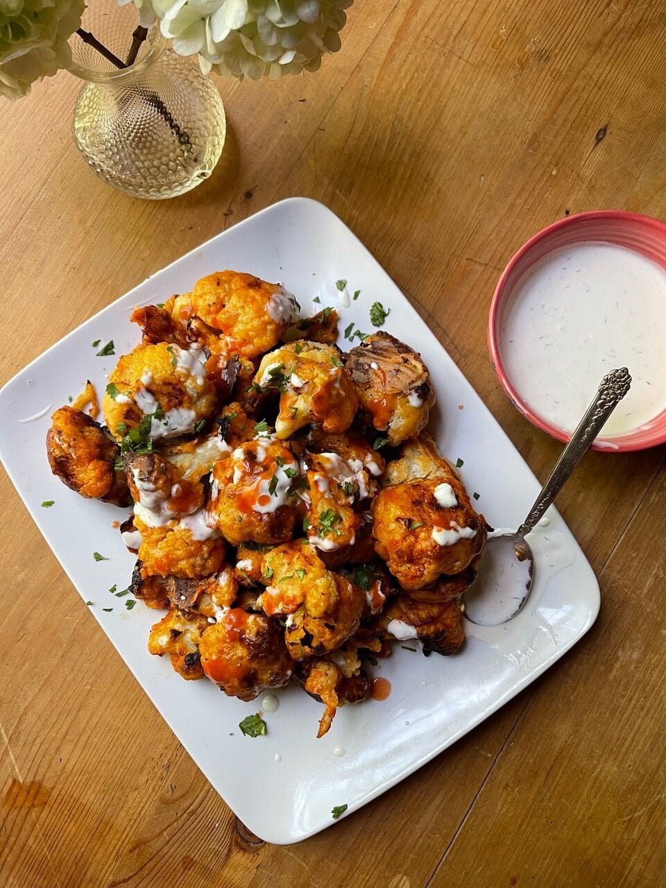 white platter with battered, roasted, sauce-covered buffalo cauliflower