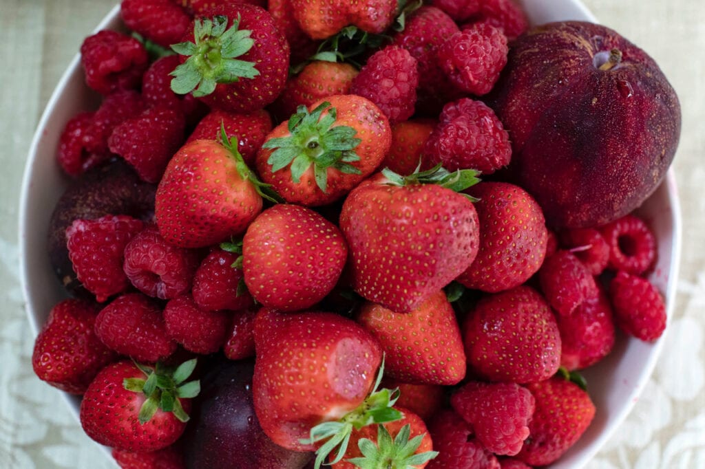 bowl of fresh strawberries and raspberries for making jam