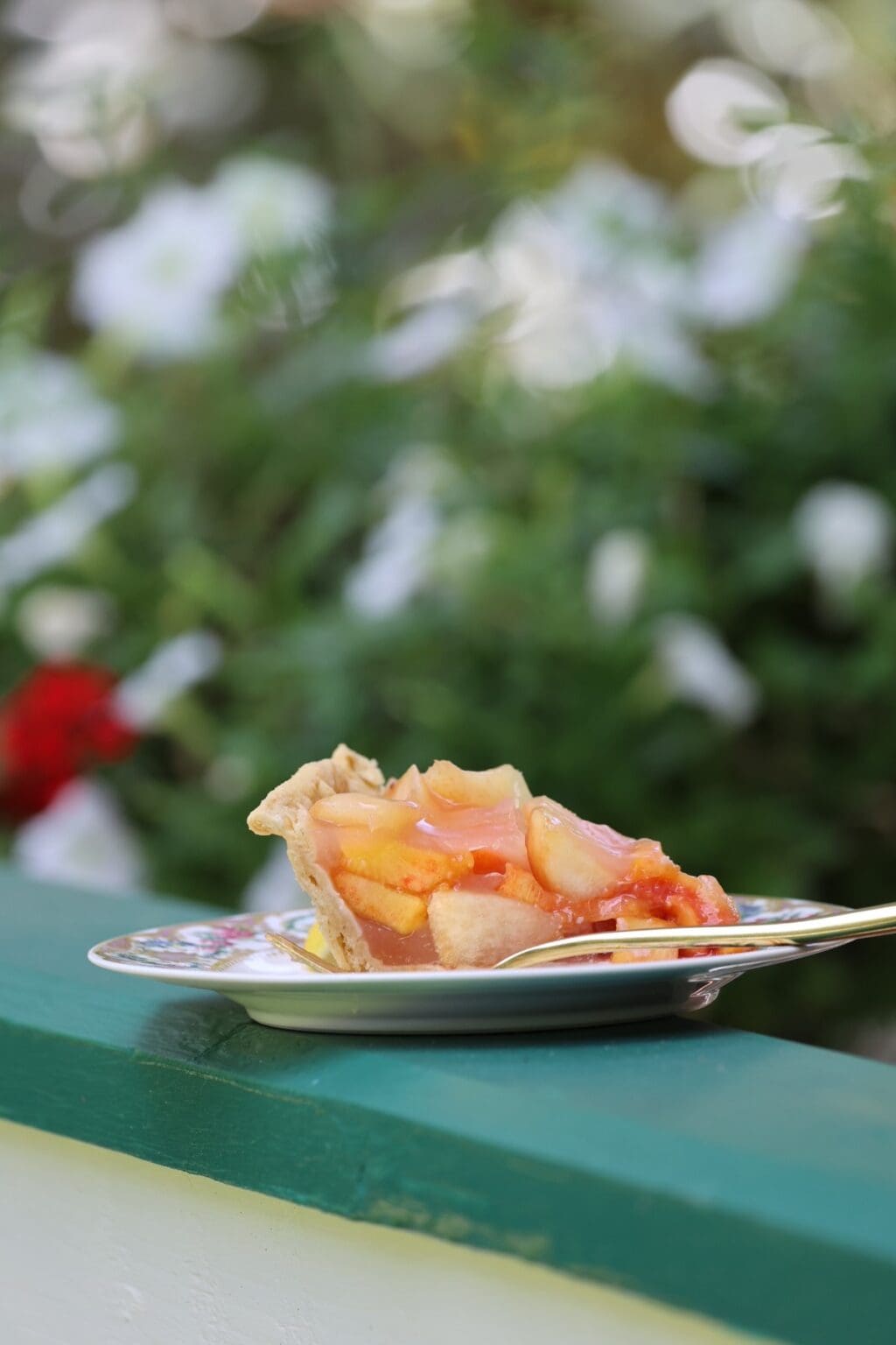 slice of chilled peach pie outdoors on china plate with fork