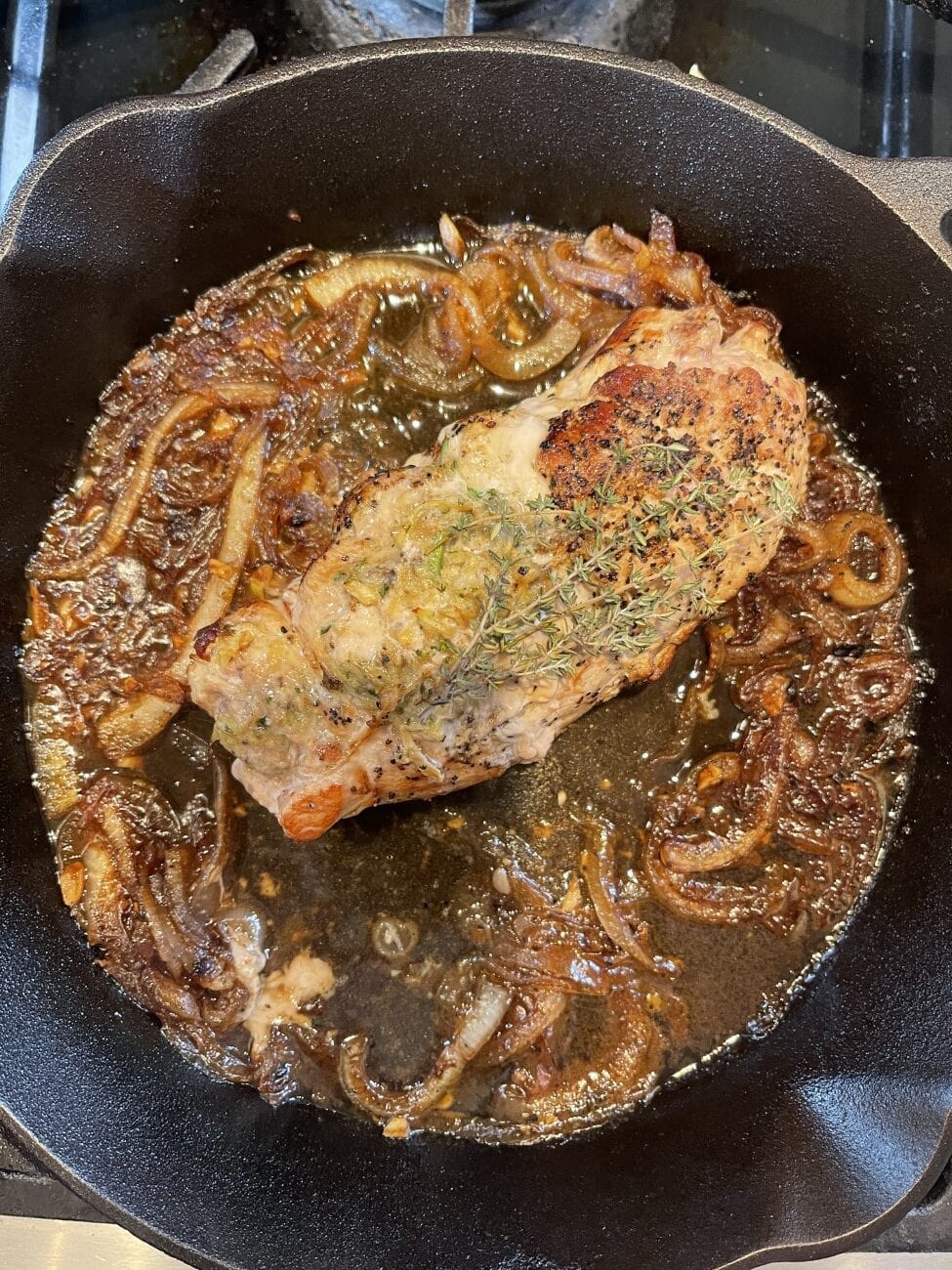 cooked stuffed turkey breast in white wine gravy in cast-iron skillet