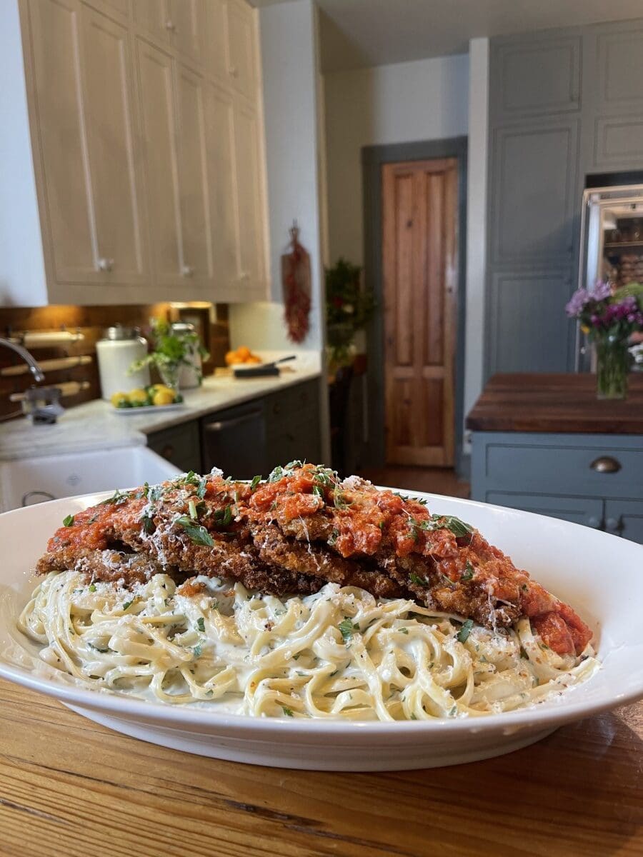 white plate full of fettucine alfredo with venison parmesan and marinara - Stacy Lyn's kitchen in background