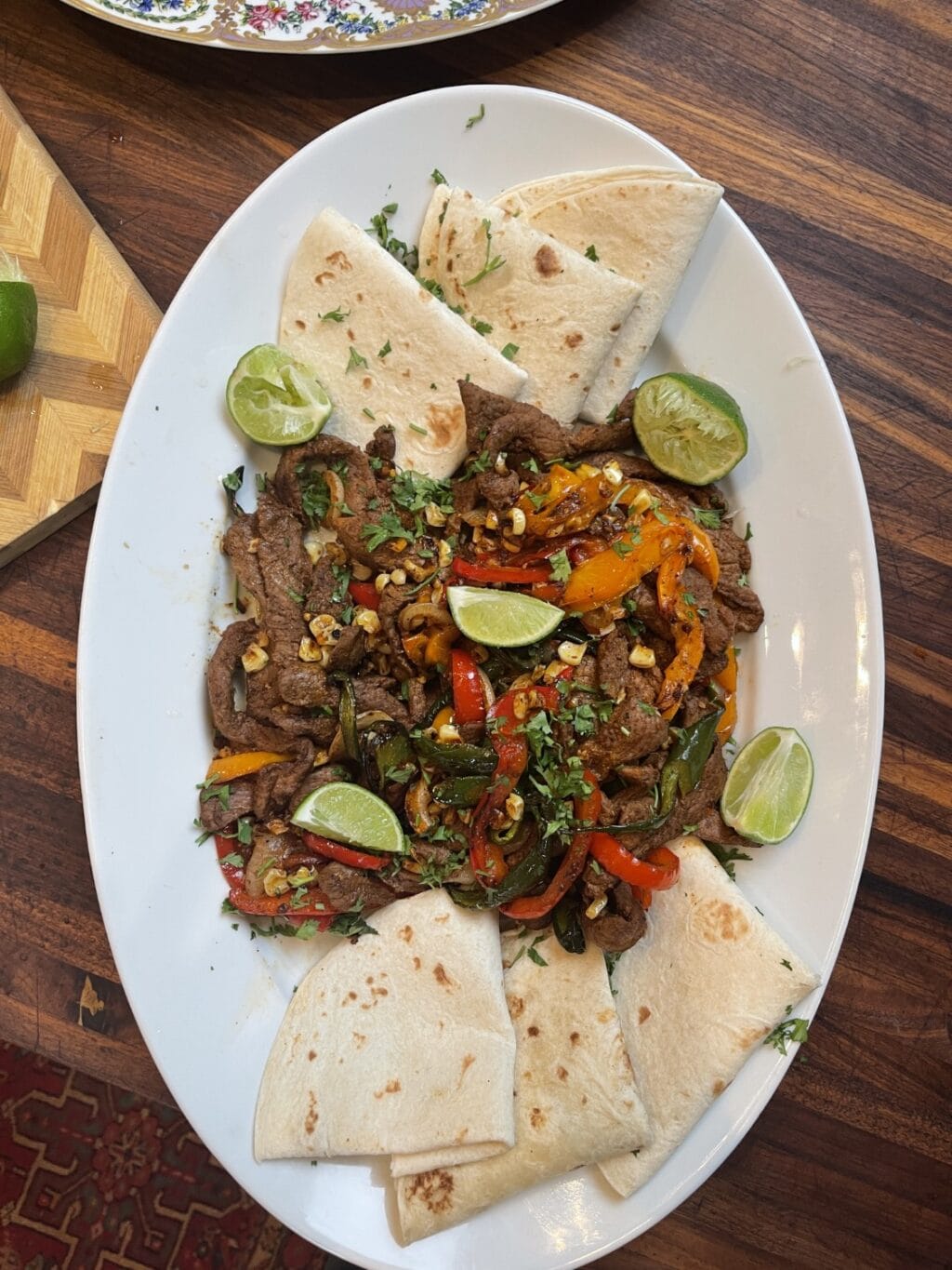 vertical shot of venison fajitas with venison, veggies, and tortillas on white platter